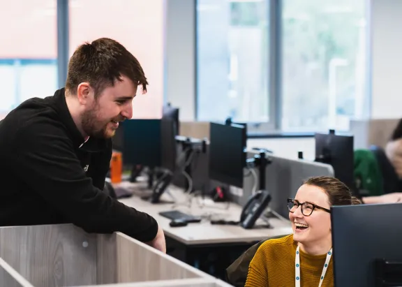 2 CAS colleagues at a computer smiling in a an office setting